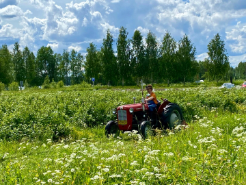 Isä Nasari ajaa traktorilla Valamon luostarin pelloilla