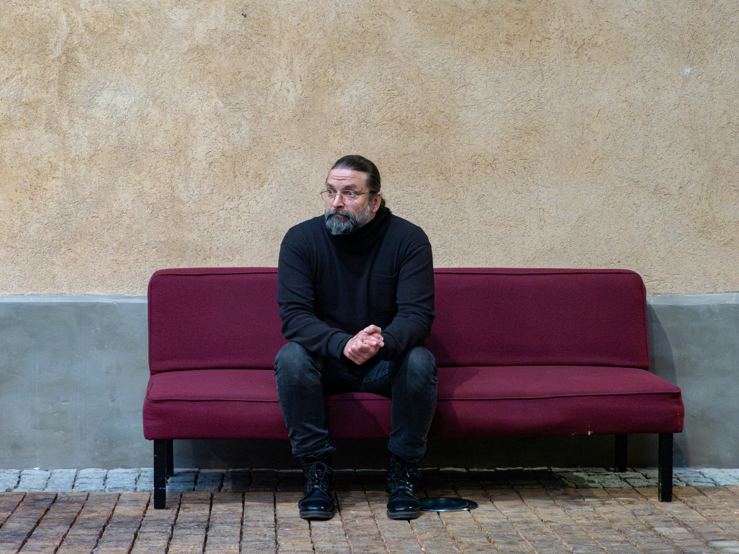 Riko Saatsi istuu punaisella sohvalla