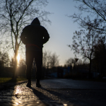 Yksinäinen mies kävelee aamuauringossa