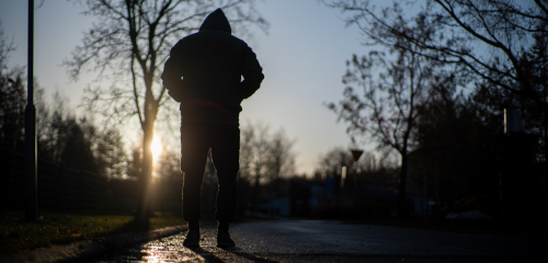 Yksinäinen mies kävelee aamuauringossa