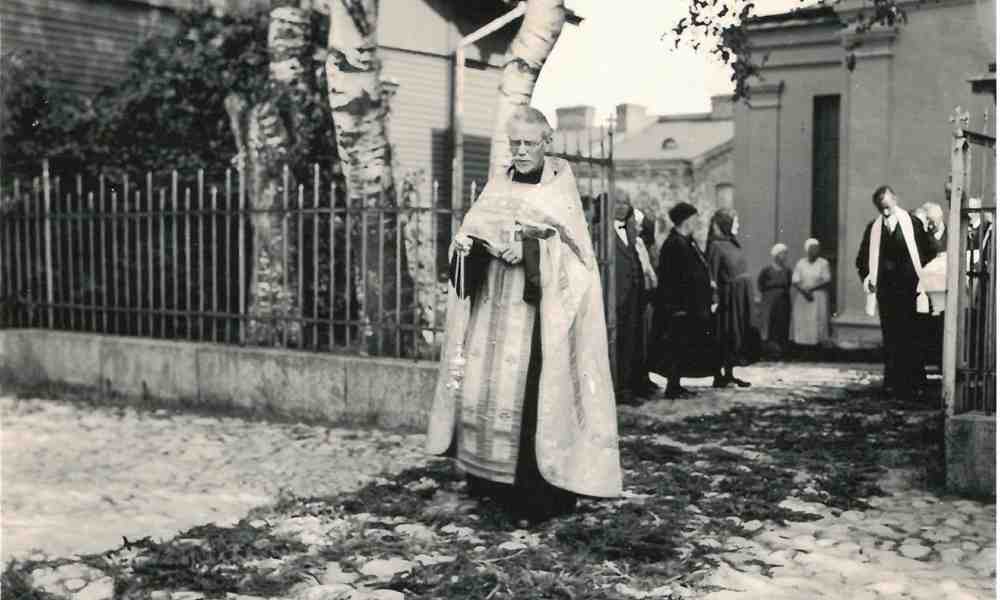 Rovasti Arsenij Razumov linnoituksen kirkon edessä vanhassa mustavalkoisessa valokuvassa