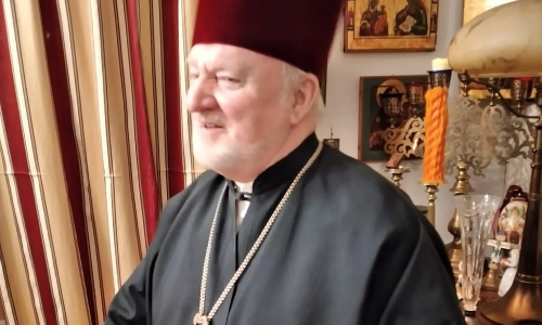 Rovasti Juhani Härkin kuvattuna profiilissa korkeassa päähineessä ja musta viitta yllään